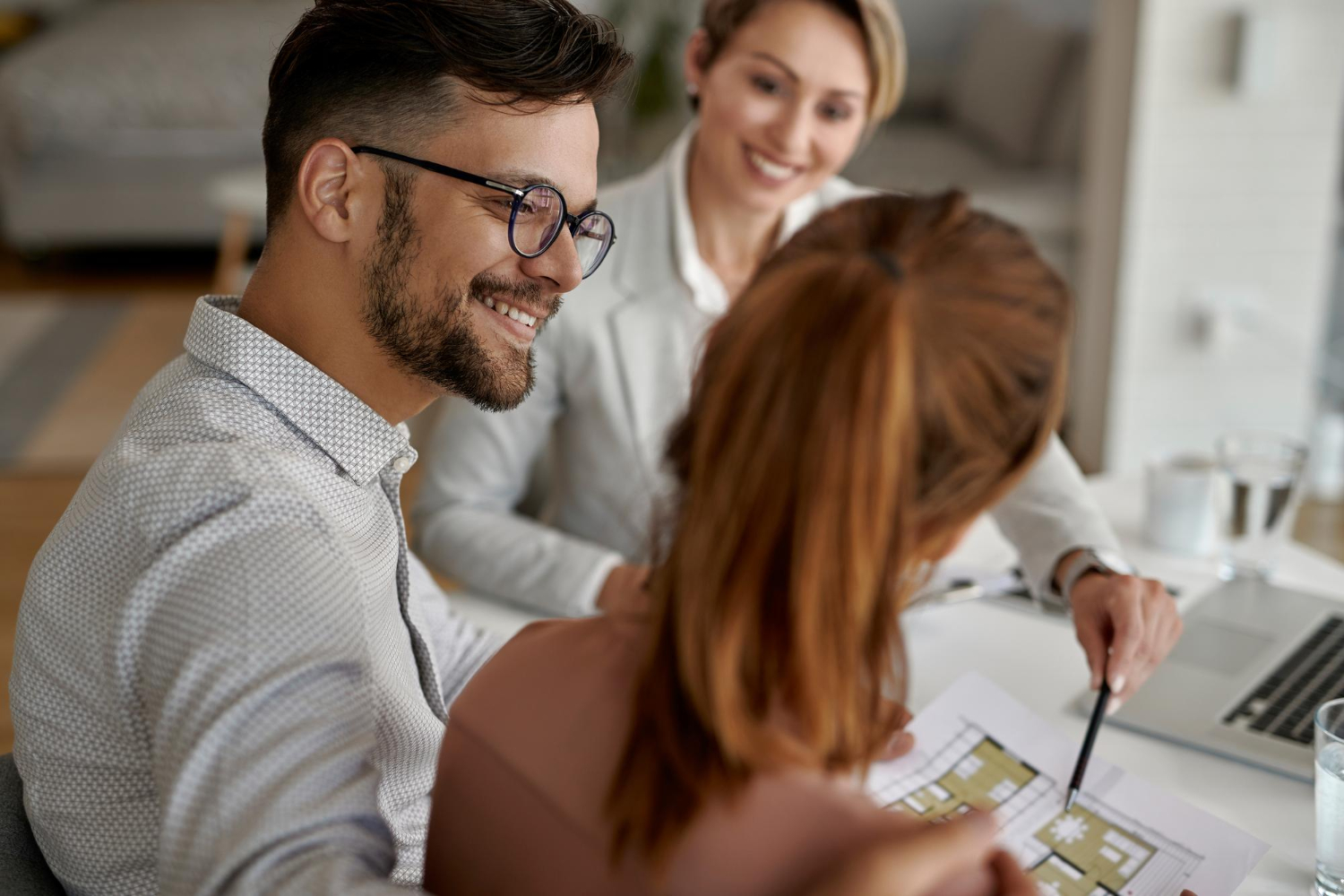 Jeune couple heureux et leur agent immobilier ayant une réunion au bureau.