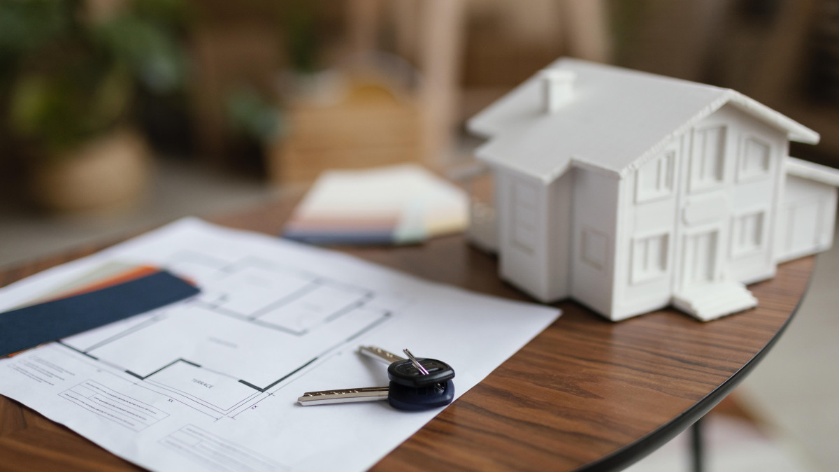 Les plans d'une maison sont posés sur une table avec un jeu de clé à côté. 